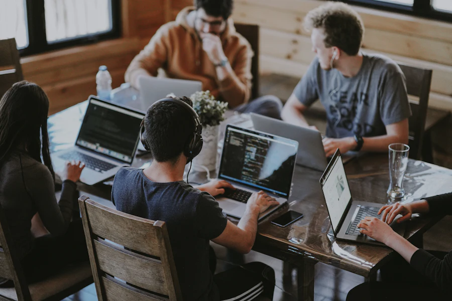 A team of technology professionals working together on laptops around a shared table